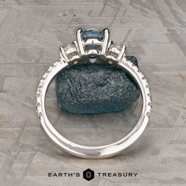 The Pave "Dryope" ring in platinum with 1.15-carat Montana sapphire The Pave "Dryope" ring in platinum features a 1.15-carat Montana sapphire centerpiece and side stones, displayed upright on a rough blue mineral with the Earth's Treasury logo below.
