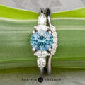 The "Tigrina" ring in platinum with a 1.25-carat Montana sapphire and the "Electra" band in platinum are displayed together on a green leaf.