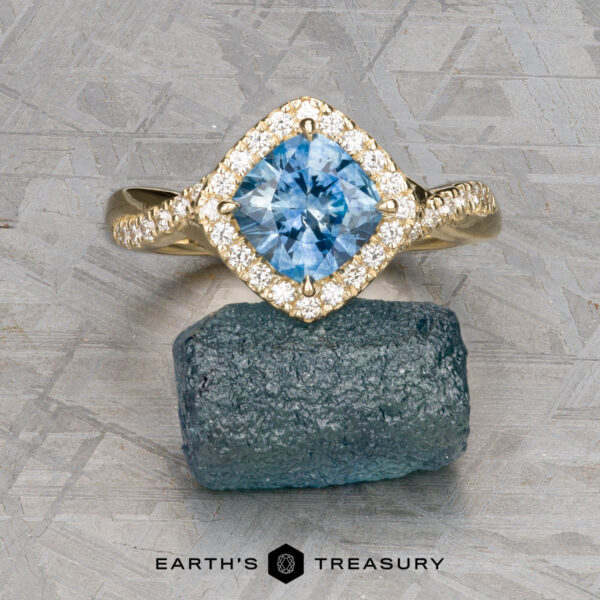 The "Yvette" ring in 14k yellow gold with 1.64-carat Montana sapphire The "Yvette" ring, crafted in 14k yellow gold and featuring a 1.64-carat Montana sapphire, is displayed atop a rough blue stone with the “Earth’s Treasury” logo below.