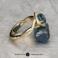 The "Yvette" ring in 14k yellow gold, featuring a 1.64-carat Montana sapphire, rests against a rough stone on a textured surface. The Earth's Treasury logo is displayed at the bottom.