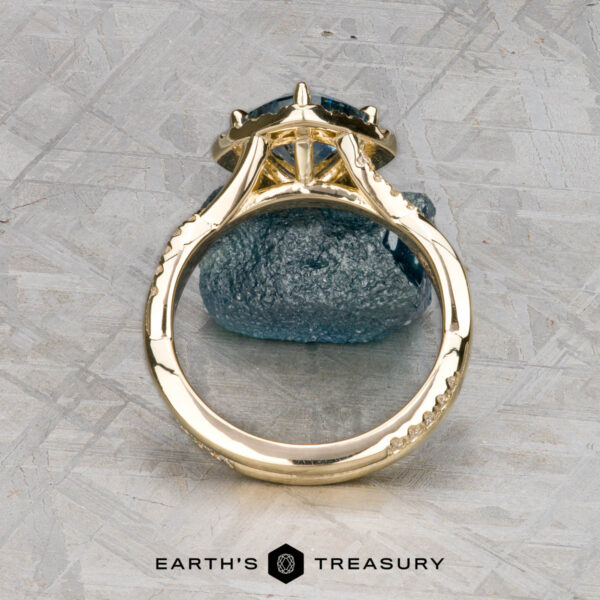 The "Yvette" ring in 14k yellow gold with 1.64-carat Montana sapphire The "Yvette" ring in 14k yellow gold with a 1.64-carat Montana sapphire is shown upright on a rough blue stone, with the Earth's Treasury logo below.