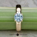 The "Davina" ring, crafted in 14k yellow gold with a 1.43-carat Montana sapphire, is displayed upright against a green bamboo stem. The "Earth's Treasury" logo appears below.