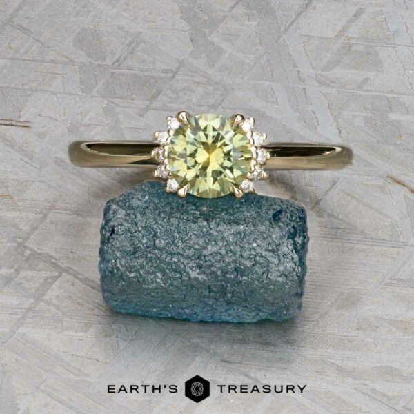 The "Wren" ring in 14k yellow gold with 0.91-carat Montana sapphire The "Wren" ring in 14k yellow gold with a 0.91-carat Montana sapphire is displayed on a rough blue crystal, with "Earth’s Treasury" logo and text at the bottom.