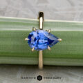 A gold Cathedral Solitaire ring, "Fisher, Matthew," with a pear-shaped blue gemstone is shown on a green background, with "Earth's Treasury" at the bottom.