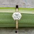The "Carmen" ring in 14k yellow gold, featuring a 1.29-carat Montana sapphire center stone and accent gems on the band, is displayed on a green leaf with the Earth’s Treasury logo below.