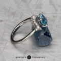 The "Veronica" ring in 14k white gold, featuring a 1.53-carat Montana sapphire and accent diamonds, is displayed on gray stone with the text "EARTH'S TREASURY" at the bottom.