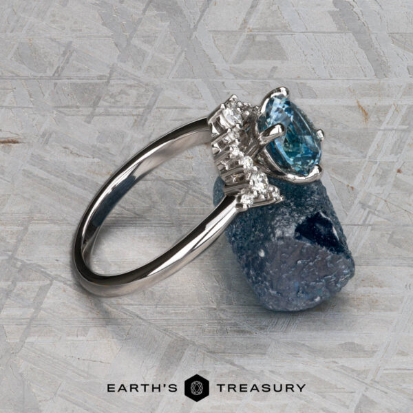 The "Veronica" ring in 14k white gold with 1.53-carat Montana sapphire The "Veronica" ring in 14k white gold, featuring a 1.53-carat Montana sapphire and accent diamonds, is displayed on gray stone with the text "EARTH'S TREASURY" at the bottom.
