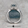 The "Veronica" ring in 14k white gold with a 1.53-carat Montana sapphire stands upright against a rough blue mineral on a textured gray background. The Earth’s Treasury logo appears at the bottom.