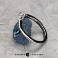 The "Veronica" band in 14k white gold, featuring a geometric design, is displayed on a rough blue gemstone, with the "EARTH'S TREASURY" logo and text below.