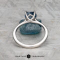 The "Elena" ring in 14k white gold with a 1.93-carat Montana sapphire is shown upright on a textured gray surface, featuring Earth's Treasury branding at the bottom.