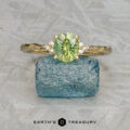 The "Aster" ring in 14k yellow gold with a 1.15-carat Australian sapphire is displayed on a rough blue stone, with the "Earth's Treasury" logo below.
