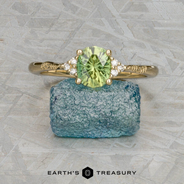 The "Aster" ring in 14k yellow gold with 1.15-carat Australian sapphire The "Aster" ring in 14k yellow gold with a 1.15-carat Australian sapphire is displayed on a rough blue stone, with the "Earth's Treasury" logo below.