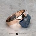 The "Theo" ring in 14k rose gold with a 0.48-carat heirloom diamond is displayed on a rough blue stone, with the Earth's Treasury logo below.