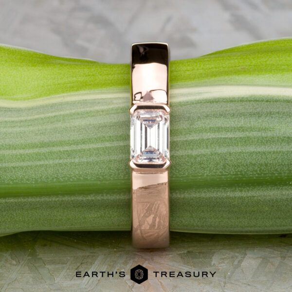The "Theo" ring in 14k rose gold with 0.48-carat heirloom diamond The "Theo" ring in 14k rose gold features a 0.48-carat heirloom diamond at its center, shown atop a green leaf with the Earth's Treasury logo beneath.