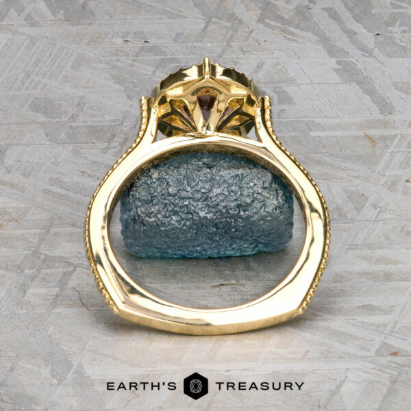 The "Marietta" ring in 18k yellow gold with 1.13-carat Montana sapphire The "Marietta" ring in 18k yellow gold with a 1.13-carat Montana sapphire stands upright on a rough blue stone surface, with Earth's Treasury logo at the bottom.