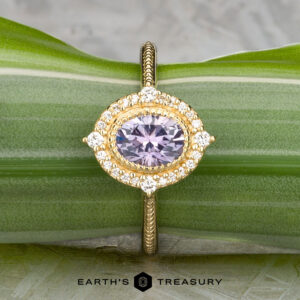 The "Marietta" ring in 18k yellow gold features a 1.13-carat Montana sapphire, accented by small white diamonds, displayed on a green leaf with the "EARTH'S TREASURY" logo and text at the bottom.
