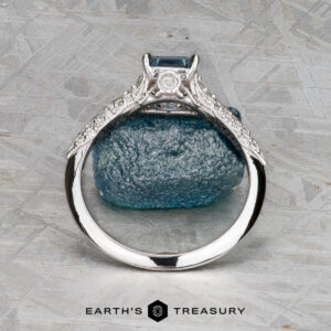 The "Anya" ring in 14k white gold features a 0.74-carat Montana sapphire in a square setting with side diamonds, displayed upright before a blue stone. Below, the words "Earth's Treasury" appear.