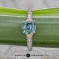 The "Anya" ring in 14k white gold, featuring a 0.74-carat Montana sapphire, is shown on a green leaf with the "Earth's Treasury" logo below.