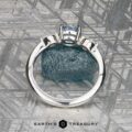 The "Zuri" ring in platinum with a 0.87-carat Montana sapphire is displayed upright on a textured gray surface, with the "Earth's Treasury" logo and text at the bottom.