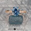 The "Musette" ring in 20k pink gold with a 3.21-carat Montana sapphire rests on a rough stone atop a geometric surface. "EARTH'S TREASURY" is shown at the bottom.