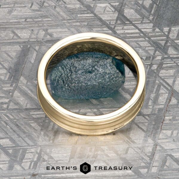 The "Silas" band in 14k yellow gold The "Silas" band in 14k yellow gold is shown with a blue textured stone on a patterned grey surface, and “Earth’s Treasury” appears at the bottom.