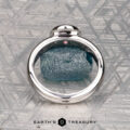 The "Lola" ring, crafted in 14k white gold and set with a 0.71-carat Montana sapphire, is showcased on a geometric-patterned surface with the text "EARTH'S TREASURY" below.