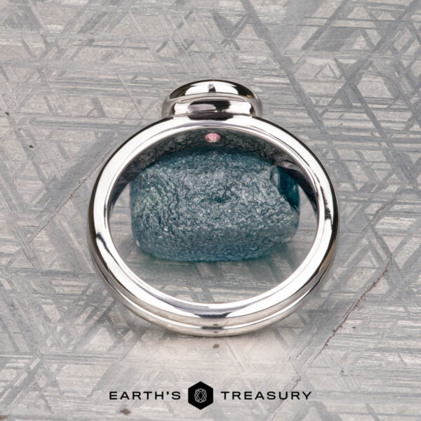 The "Lola" ring in 14k white gold with 0.71-carat Montana sapphire The "Lola" ring, crafted in 14k white gold and set with a 0.71-carat Montana sapphire, is showcased on a geometric-patterned surface with the text "EARTH'S TREASURY" below.