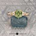 The "Chrysanthemum" ring, crafted in 14k yellow gold with a 1.46-carat Australian sapphire, is displayed atop a rough blue crystal against a textured gray background.
