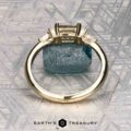 The "Athena" ring in 14K yellow gold with a 1.20-carat Montana sapphire stands upright against a blue mineral and geometric background, with the "EARTH'S TREASURY" logo at the bottom.