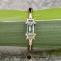 The "Athena" ring in 14K yellow gold features a 1.20-carat rectangular Montana sapphire and baguette side stones, shown on a green leaf with "EARTH'S TREASURY" at the bottom.