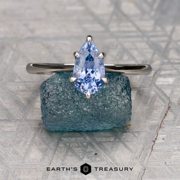The Cathedral "Anemone" ring in platinum with 1.31-carat Ceylon sapphire The Cathedral "Anemone" ring in platinum with a 1.31-carat pear-shaped Ceylon sapphire is shown on a blue-green crystal, against a geometric background, with "Earth's Treasury" beneath.