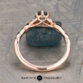 The "Kirryn" ring in 14K rose gold, featuring a 1.17-carat Montana sapphire and leaf motifs, is displayed upright on a rough blue stone background. Earth’s Treasury logo appears at the bottom.