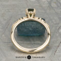 The "Blythe" ring in 14K yellow gold showcases a 0.90-carat Australian sapphire and diamond accents, displayed on a blue-green stone with the "Earth's Treasury" logo below.