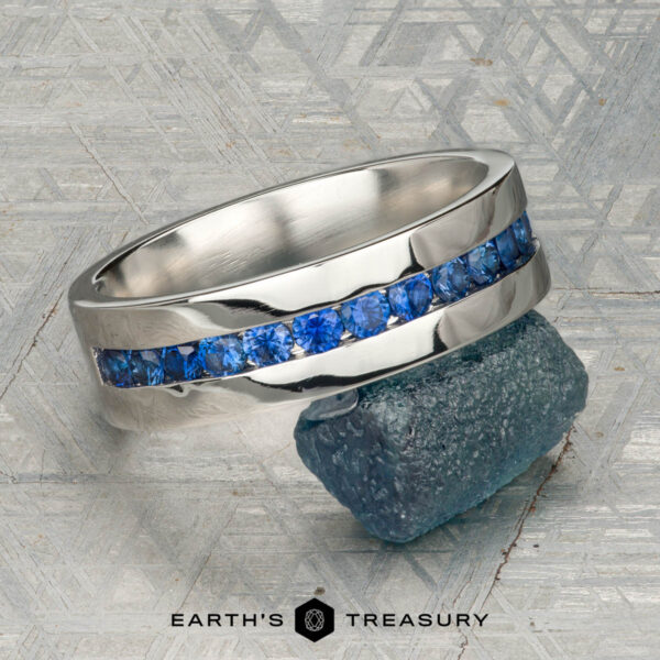 The "Atlas" ring in platinum A platinum Atlas ring encircling a rough blue gemstone, displayed on a textured gray surface with "Earth's Treasury" at the bottom.