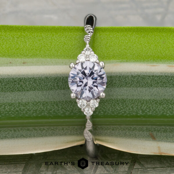 The "Aster" ring in platinum with 0.80-carat Montana sapphire The "Aster" ring in platinum, featuring a 0.80-carat Montana sapphire and accent stones, rests on a green leaf with the Earth's Treasury logo at the bottom.