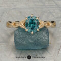 The "Kirryn" ring in 14K yellow gold with a 1.37-carat Montana sapphire, featuring leaf accents, is shown on a rough blue mineral with the "Earth's Treasury" logo below.