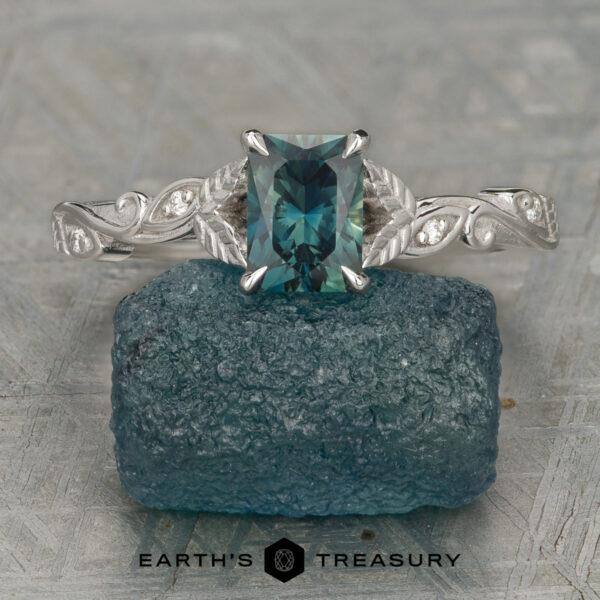 Stacked from 14 images. Method=B (R=14,S=2) A blue-green "Stacked from 14 images. Method=B (R=14,S=2)" ring with a detailed silver band rests on a rough blue stone, displayed on a textured surface. The "Earth's Treasury" logo is visible at the bottom.
