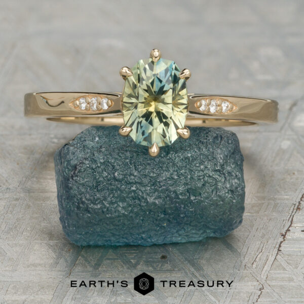 Stacked from 16 images. Method=B (R=7,S=2) The Carmen ring featuring an oval light green gemstone with small diamonds on the band rests on a blue-green stone. The "EARTH'S TREASURY" logo and text are visible below.