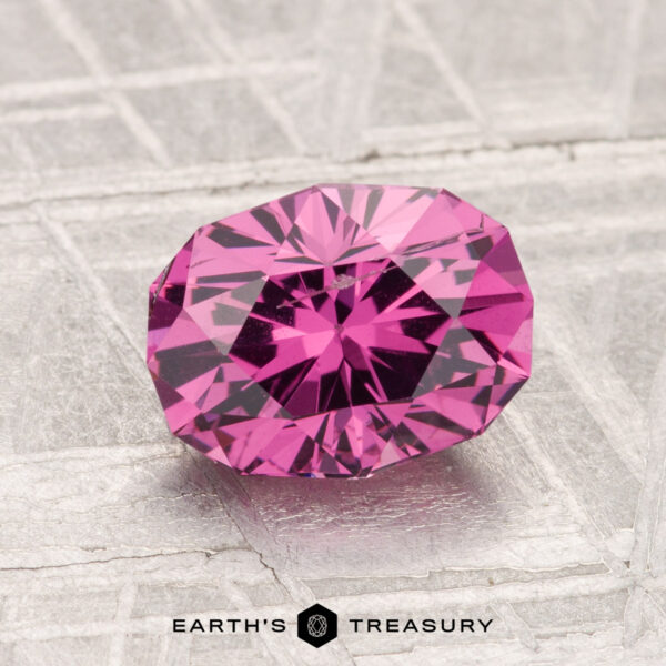 1.81-Carat Mahenge Garnet A 1.81-carat Mahenge Garnet, faceted in an oval cut, is displayed on a textured light gray surface with the "Earth's Treasury" logo at the bottom.