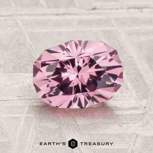 1.79-Carat Mahenge Garnet A 1.79-carat Mahenge Garnet with an oval cut and multiple facets is shown on a textured light gray surface, with the Earth's Treasury logo at the bottom.