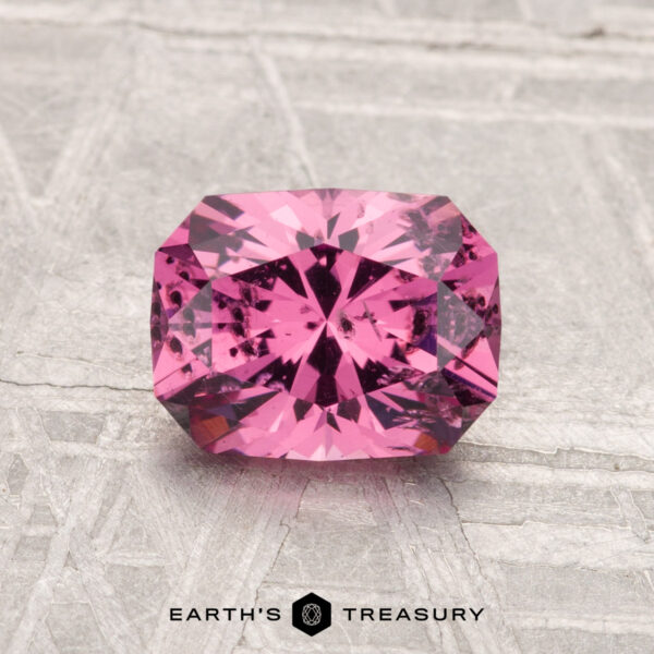 1.38-Carat Mahenge Garnet A 1.38-carat Mahenge Garnet with a rectangular radiant cut is displayed on a textured gray surface, with "Earth's Treasury" shown below.