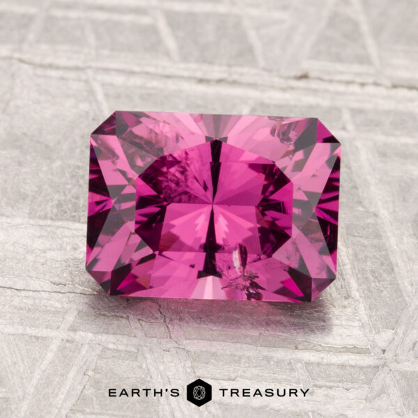 2.37-Carat Mahenge Garnet A 2.37-carat Mahenge Garnet with a rectangular cut shown on a textured gray surface, featuring "EARTH'S TREASURY" at the bottom.