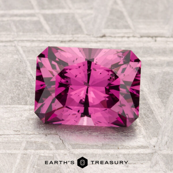 2.27-Carat Mahenge Garnet A 2.27-carat Mahenge Garnet with a radiant cut is shown on a textured light gray surface, with "EARTH'S TREASURY" displayed below.