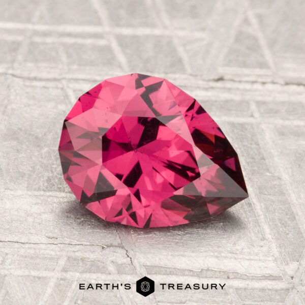 1.77-Carat Mahenge Garnet A 1.77-carat Mahenge Garnet, pear-shaped and faceted, is displayed on a textured gray surface with the "Earth's Treasury" logo at the bottom.