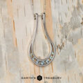 The "Twilight" ring keeper necklace in 14K white gold features a teardrop design with seven small gemstones at the base, shown on a light wooden background with the "Earth's Treasury" logo below.
