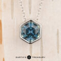 The Build Your Own "Shimmer" pendant in 14k white gold features a 1.62-carat Montana sapphire, shown against a light textured background with the "Earth's Treasury" logo at the bottom.