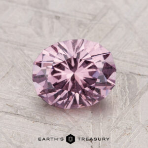 1.82-carat round brilliant-cut pastel pyrope garnet displayed on a textured grey surface with the "Earth's Treasury" logo at the bottom.