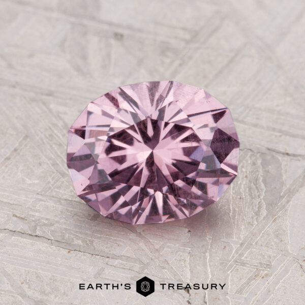 1.82-Carat Garnet 1.82-carat round brilliant-cut pastel pyrope garnet displayed on a textured grey surface with the "Earth's Treasury" logo at the bottom.
