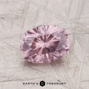 A 1.50-carat faceted, oval-shaped pink garnet is displayed on a textured metallic surface with "EARTH'S TREASURY" at the bottom.
