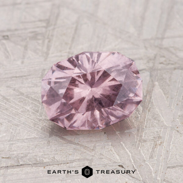 1.50-Carat Garnet A 1.50-carat faceted, oval-shaped pink garnet is displayed on a textured metallic surface with "EARTH'S TREASURY" at the bottom.